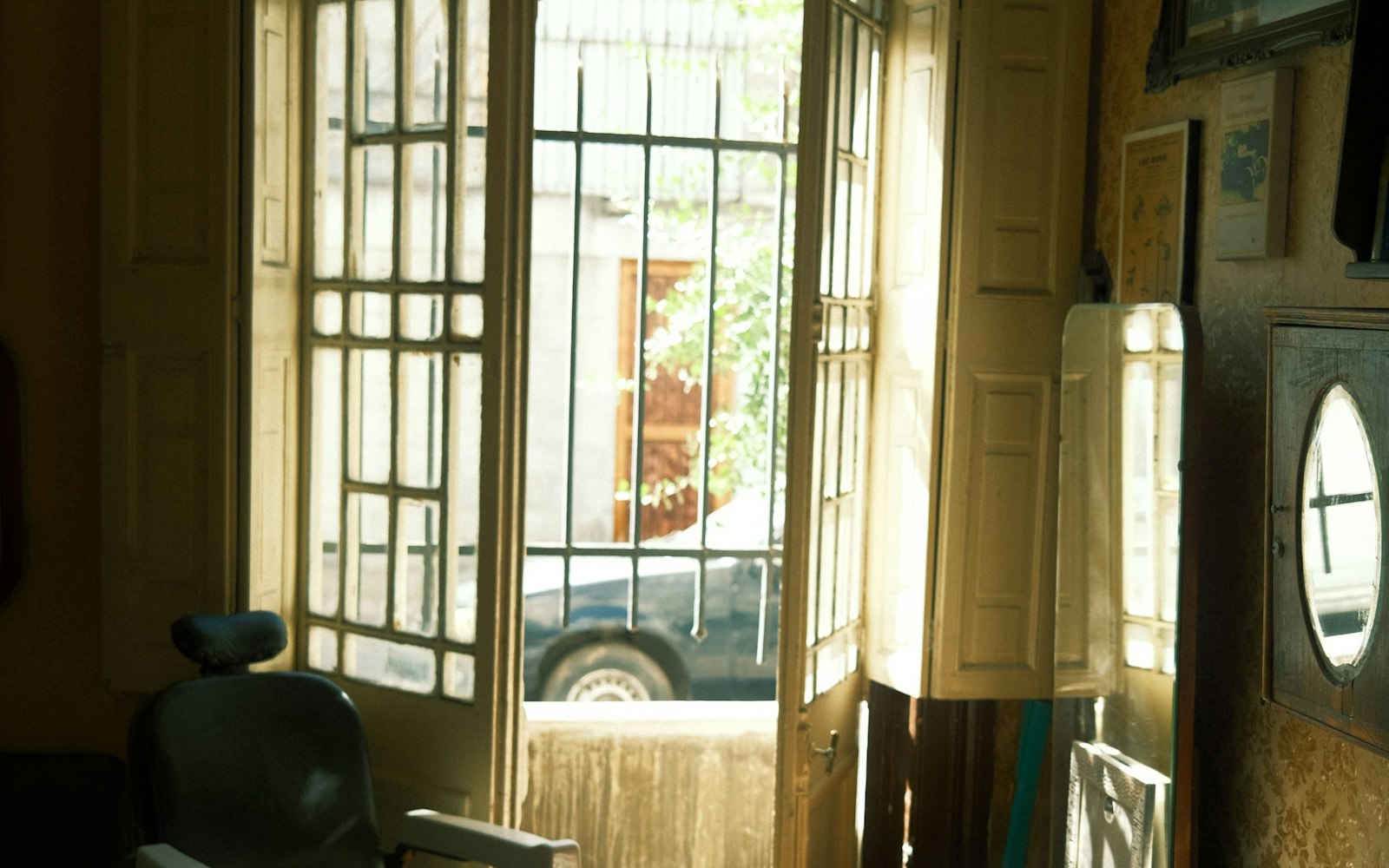 A barber chair beside the shop's tall front window with daylight coming through